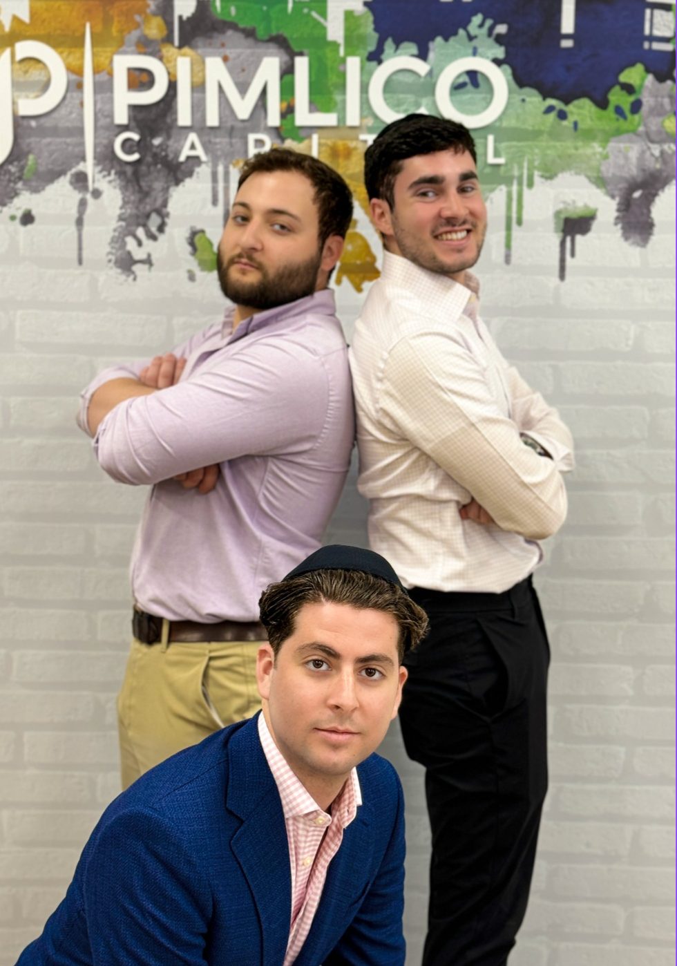 Three teammates at the Pimlico Capital wall